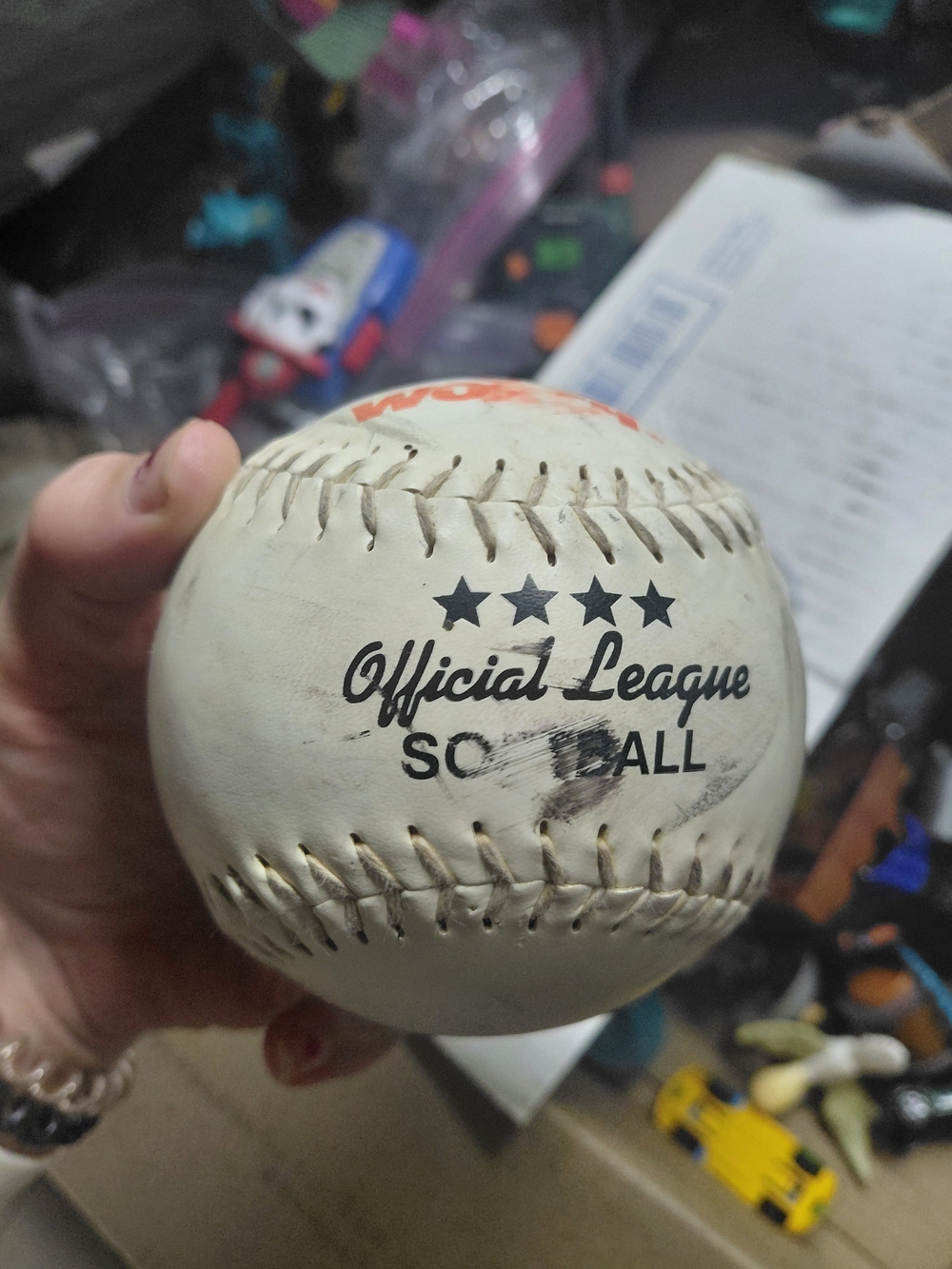 Worth Official League softball, featuring red stitched seams and a white cover.
